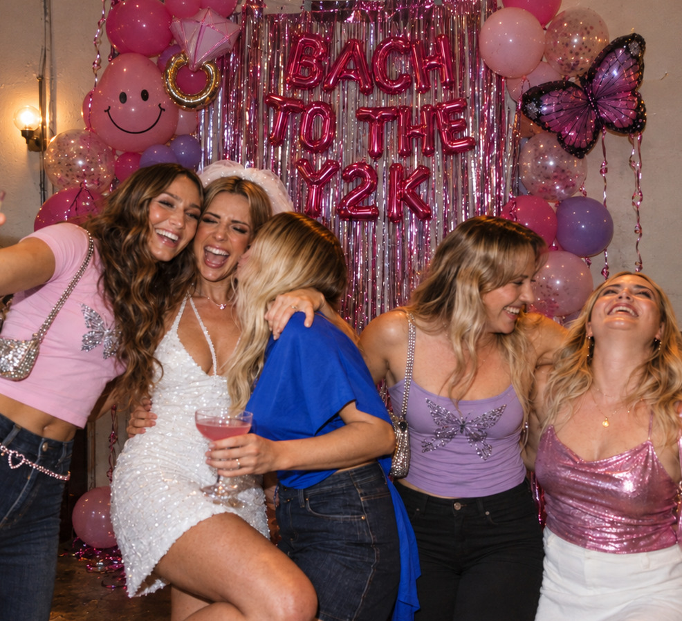 A bride to be in a veil laughing with four friends under Y2K balloon letters
