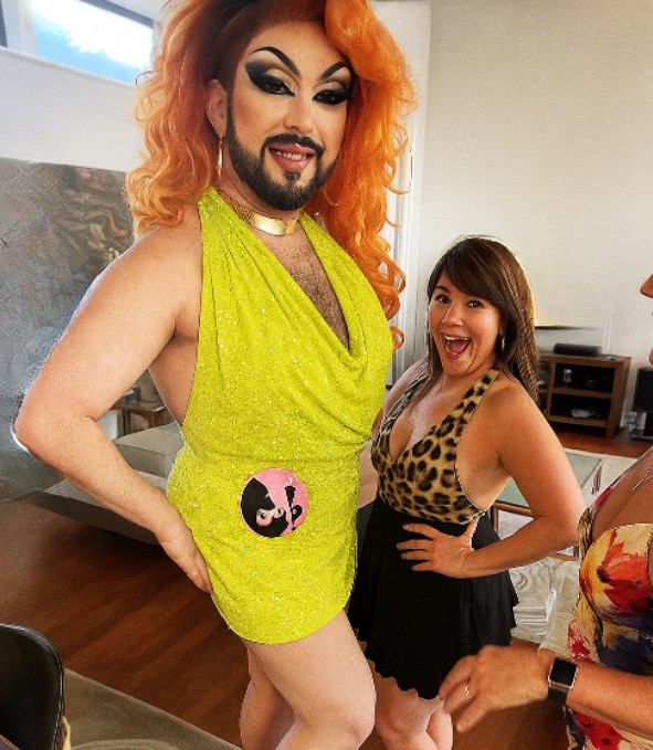 Our drag queen in a lime sequin mini and a copper wig striking a pose while a hen in leopard print screams with delight
