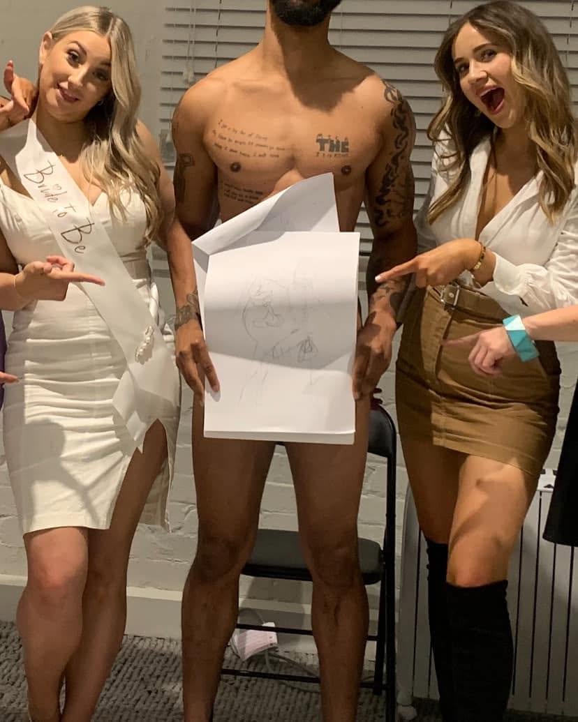 Two hens pointing at the life drawing model, who is holding up a drawing of himself