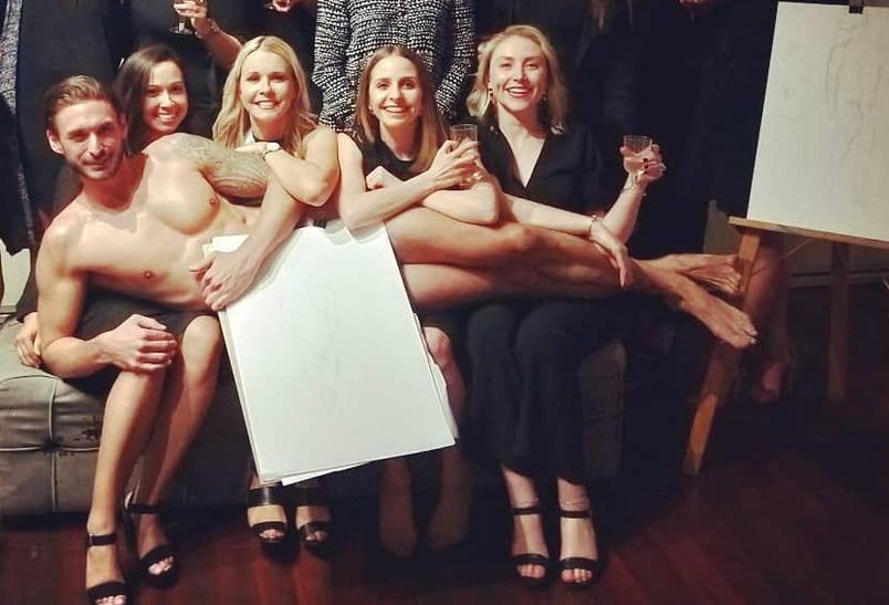Five hens on a couch with the model across their laps, holding a drawing board