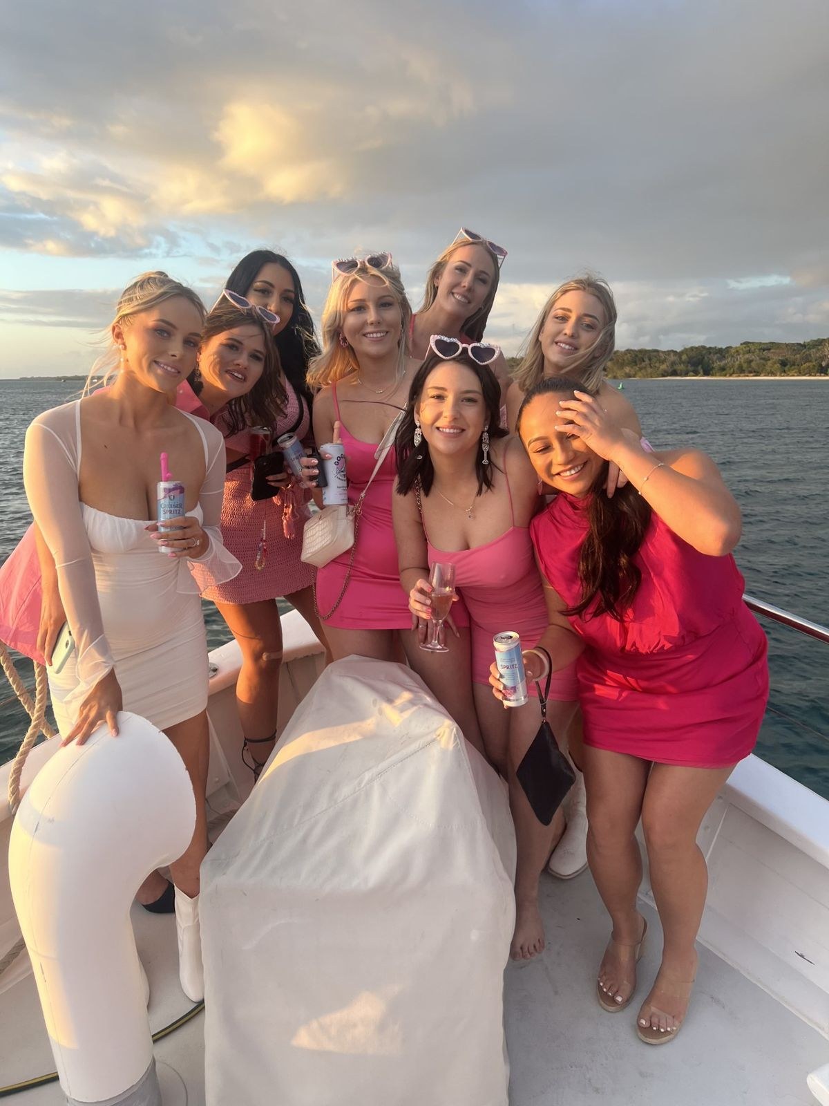 A hens group in pink on the deck of a boat at sunset