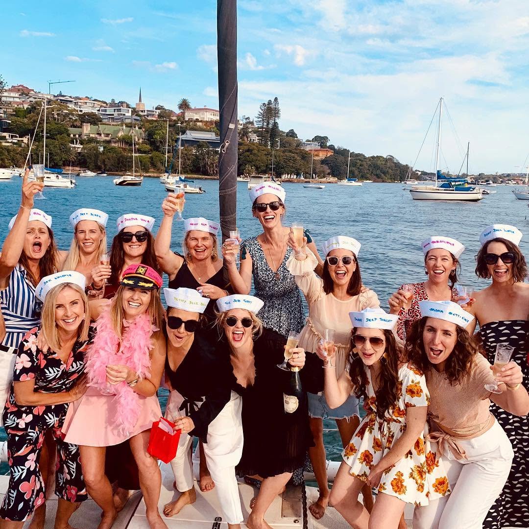A hens group in sailor hats toasting champagne on a yacht