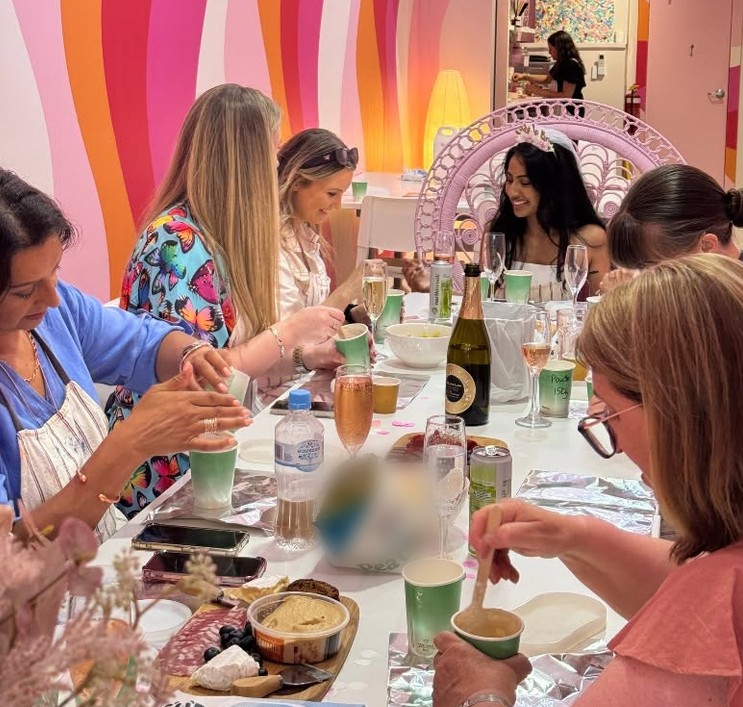 The bride in a tiara on a peacock chair at the end of a long table of friends, grazing boards and bubbly