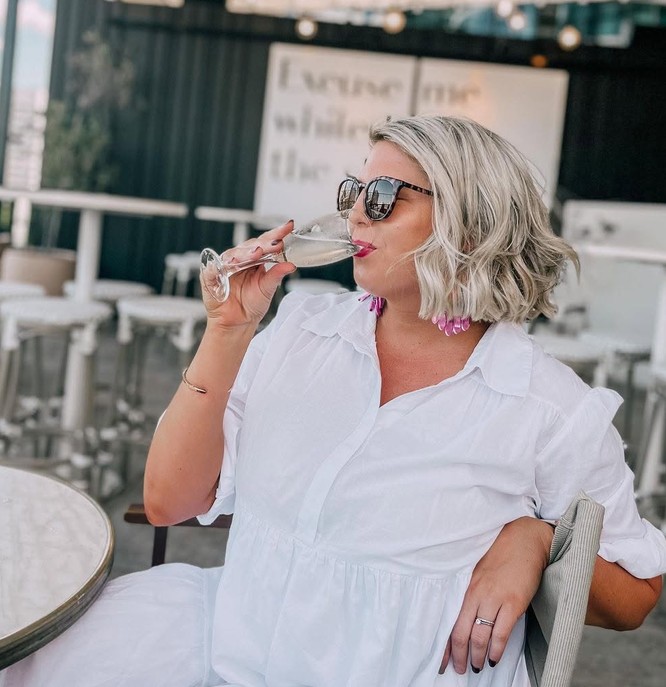 A friend in a white shirt and sunglasses sipping bubbles on a terrace