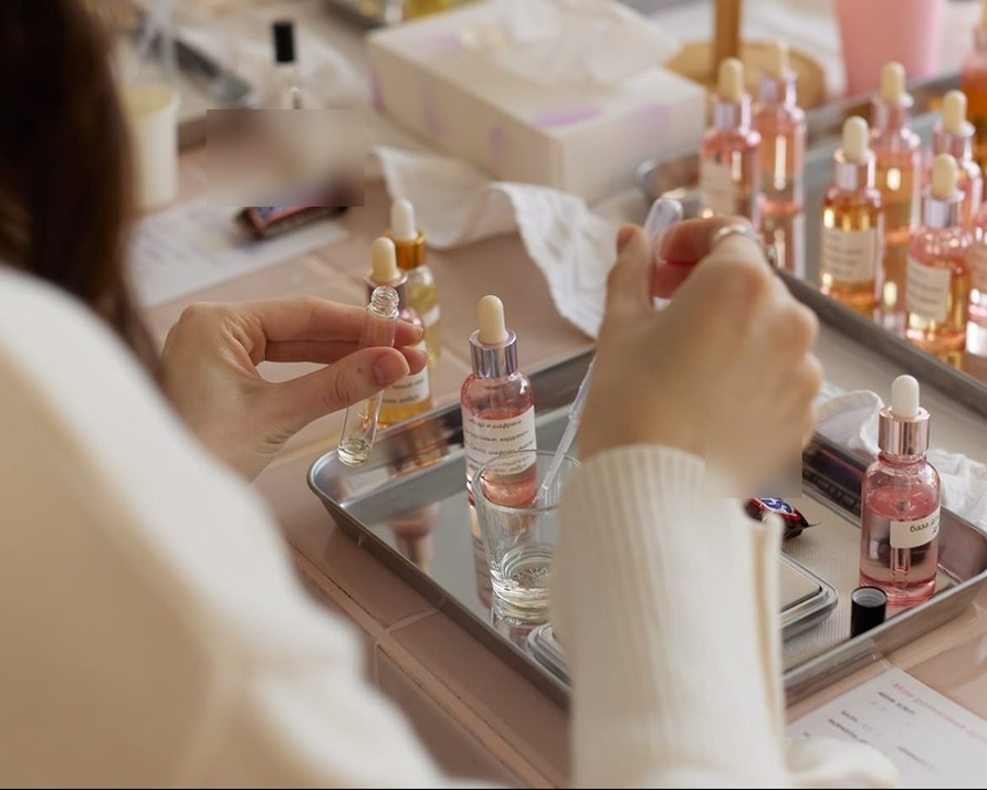 A guest pipetting pink perfume over a tray of little bottles