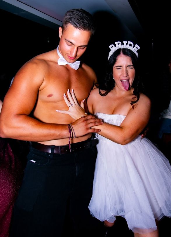 The bride in a Bride tiara poking her tongue out beside a performer in a bow tie