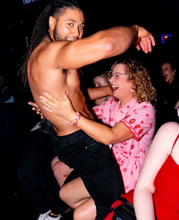 A shirtless performer dancing with a laughing woman in a pink top