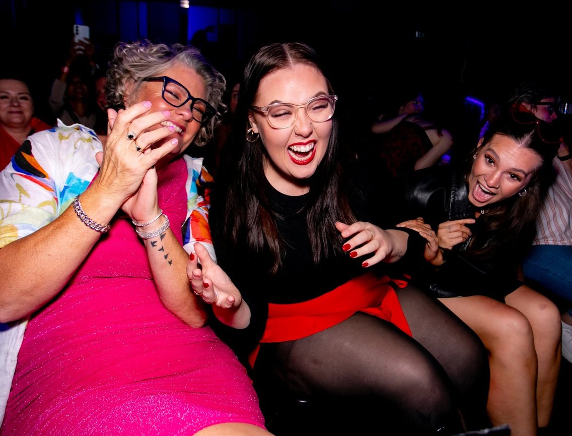 An older woman and a younger woman in the front row, both laughing and cheering