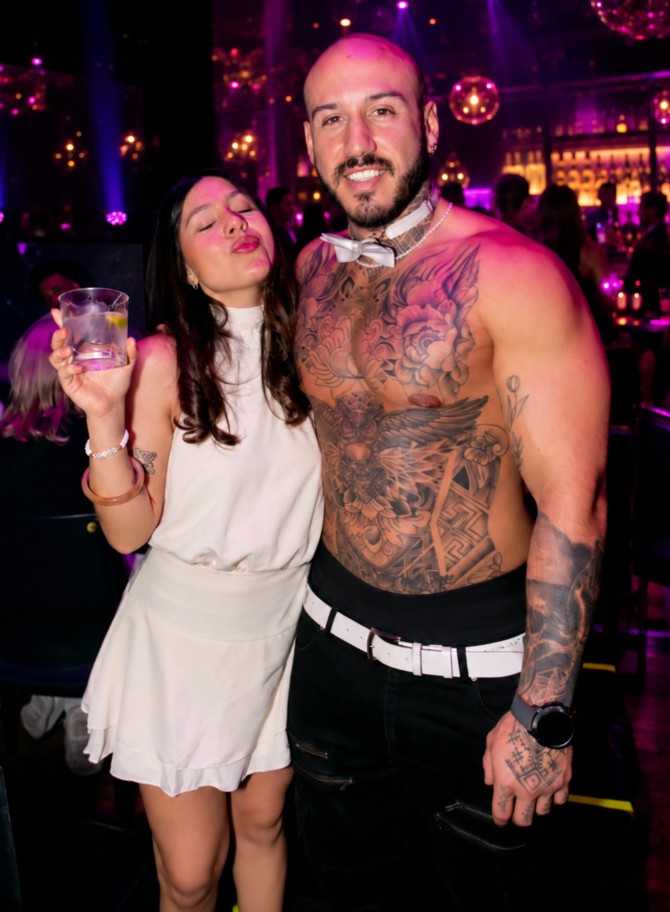 A hen with her drink pouting for the camera beside our tattooed topless waiter in his bow tie