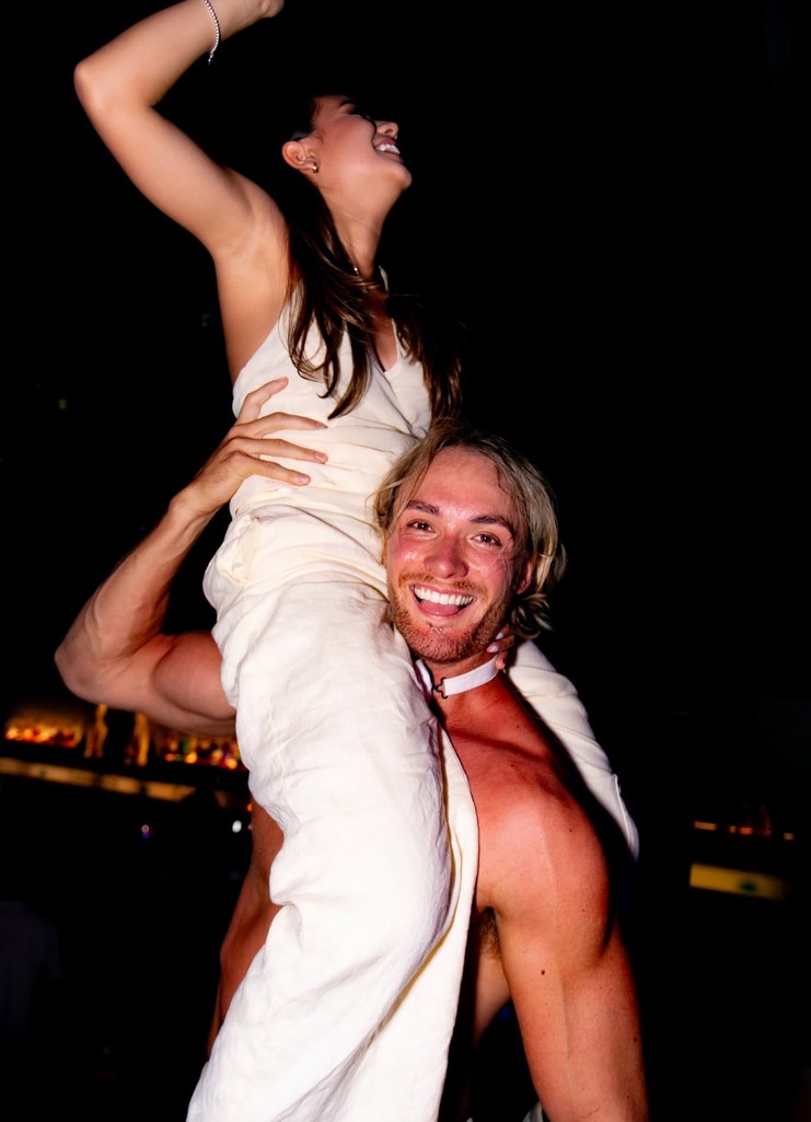 Our topless waiter carrying a laughing hen on his shoulders, her arm in the air