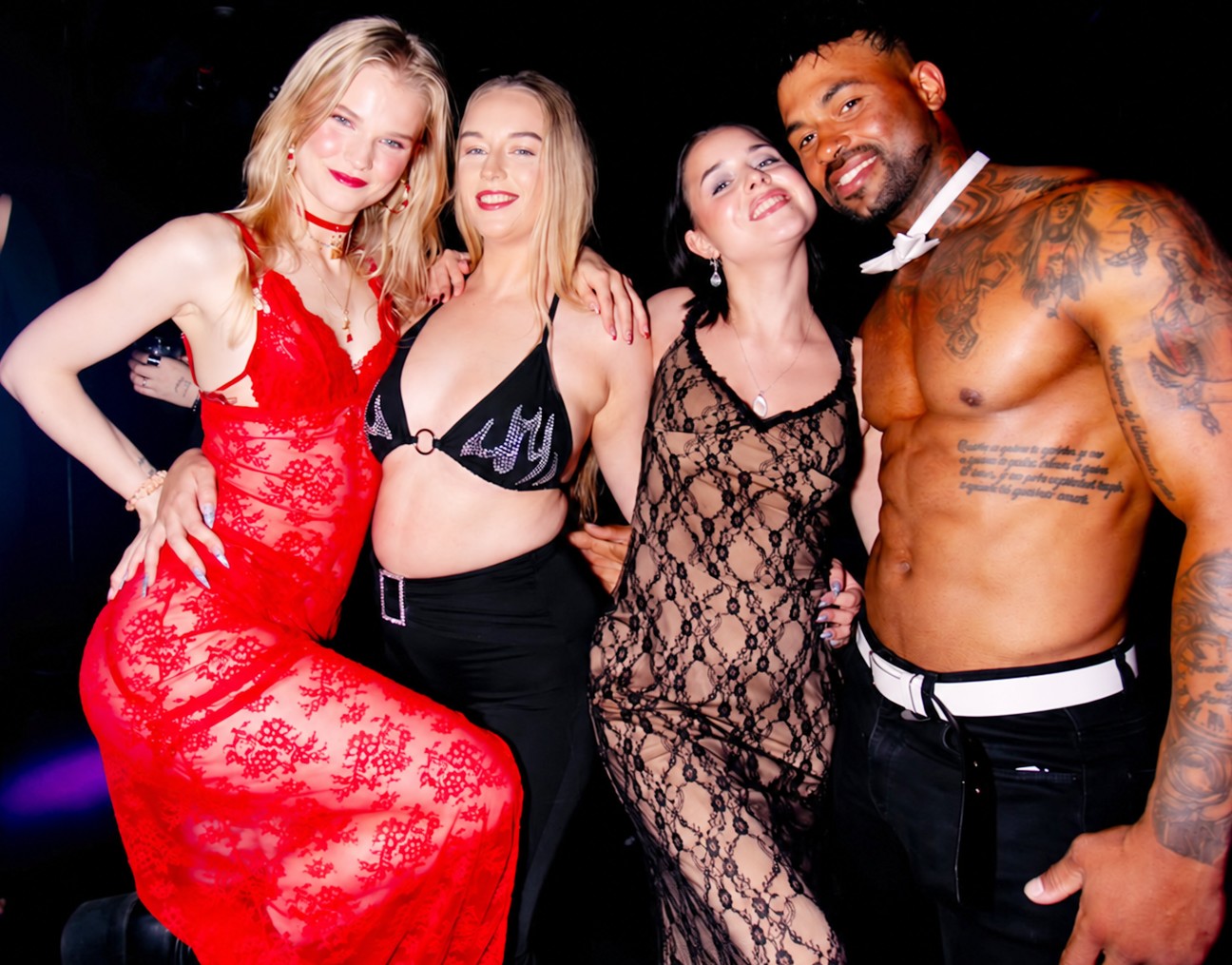 Three friends in lace and sparkle posing with our tattooed topless waiter in his bow tie