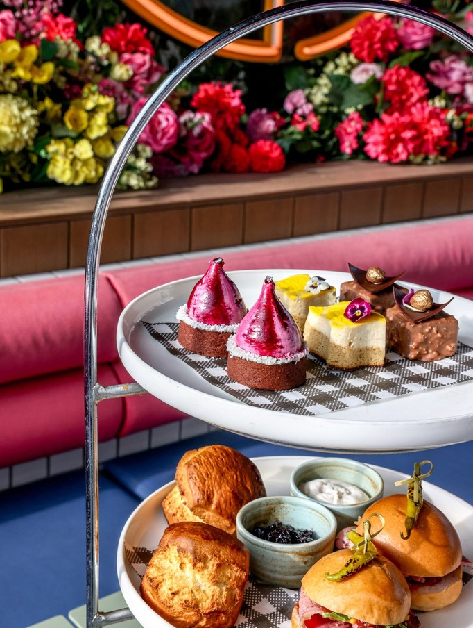 Scones with jam and cream under a tier of little cakes