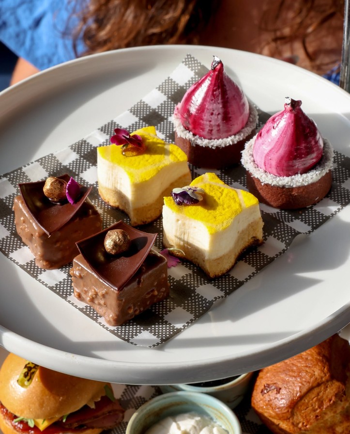 The sweets tier: chocolate slices, little cheesecakes and pink meringue domes
