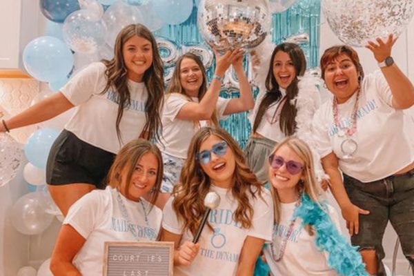 Hens group in matching white tees with disco balls and blue balloons
