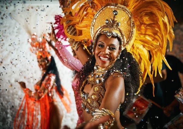 Samba dancers in gold feather headdresses performing among confetti