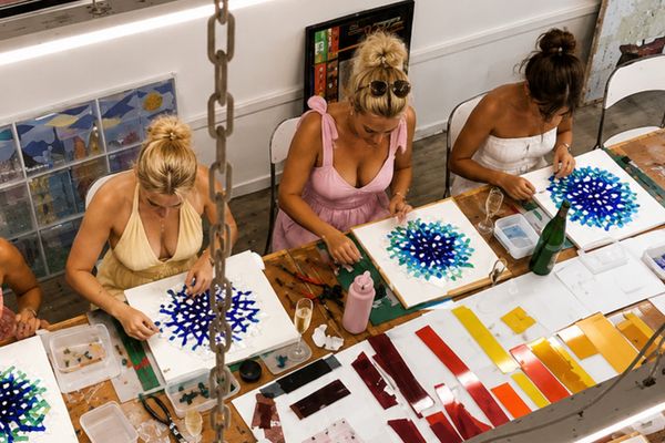 Looking down on guests laying out coloured glass designs at a studio class