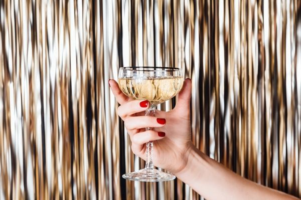 A coupe of bubbles held up against a gold tinsel curtain