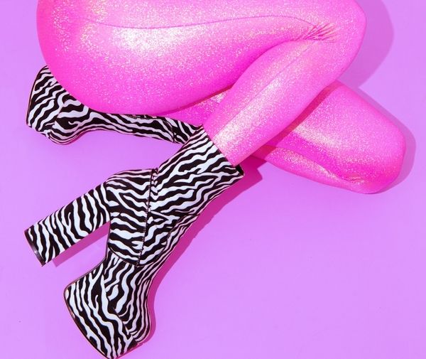 Legs in pink glitter tights and zebra print platform boots on a purple background