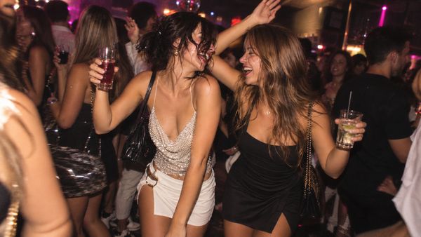 Friends dancing with drinks on a crowded nightclub dance floor