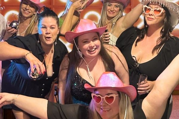 Friends in pink cowgirl hats and heart sunglasses cheer in a pink neon room