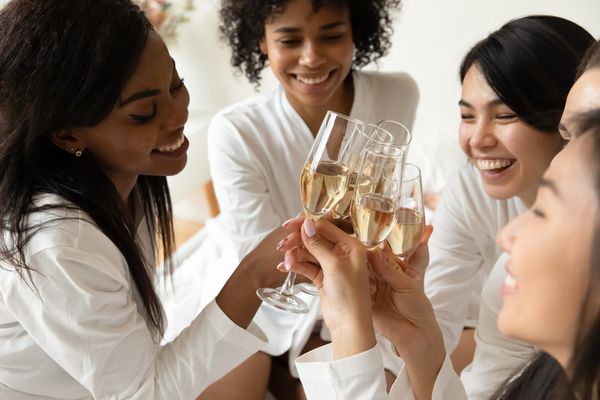 Friends in white robes smiling and clinking glasses of bubbly