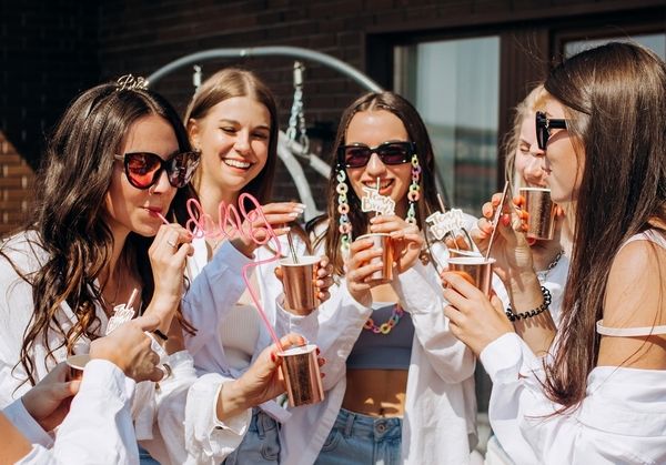 a group of women laughing outside in the sunshine drinking bubbly from flutes