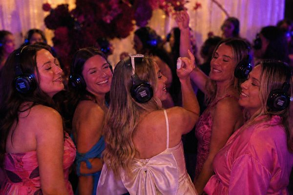 Hens in pink dancing with glowing headphones on, eyes closed, singing along