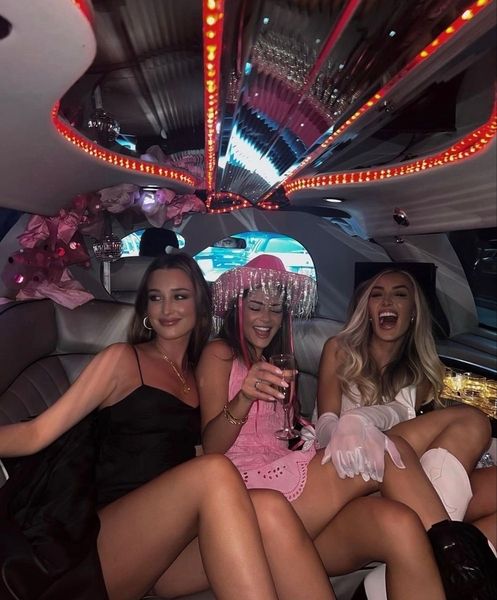 Friends laughing in the back of a limousine, one in a sequin cowgirl hat