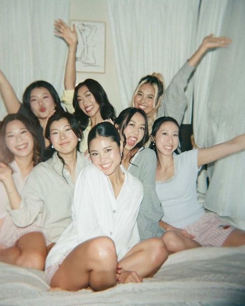 A hens group in pyjamas cheering together on a bed