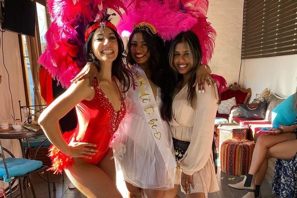 Bride with a burlesque dancer in a red costume and pink feather headdress
