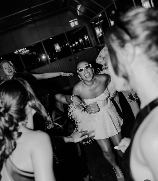 A bride to be in heart sunglasses dancing with her friends in black and white