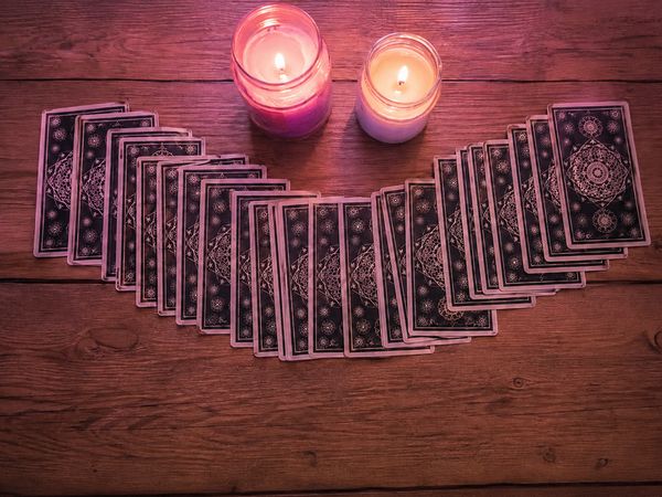 A spread of tarot cards beside two lit pink candles