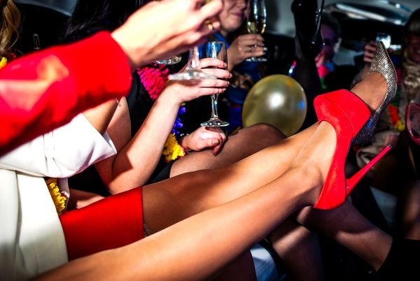 Friends with bubbles and red heels up in the back of a party limousine