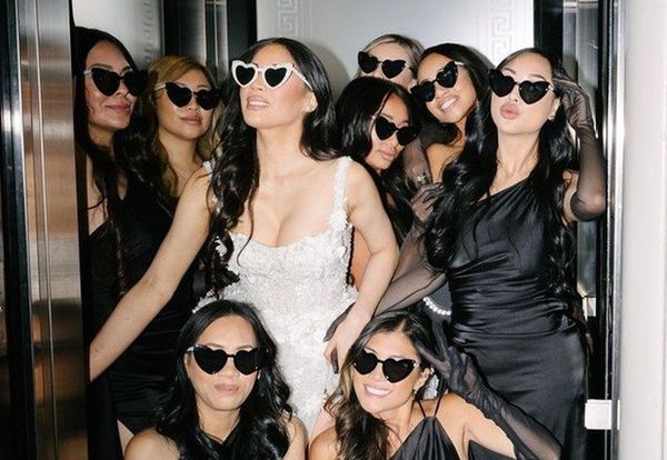The bride in white lace with her crew in black satin and heart sunglasses squeezed into a lift