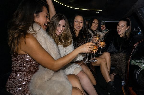 A group of friends laughing and toasting in the back of a limousine