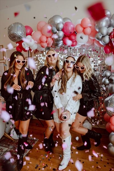 A hens group in white sunglasses dancing among balloons and falling confetti
