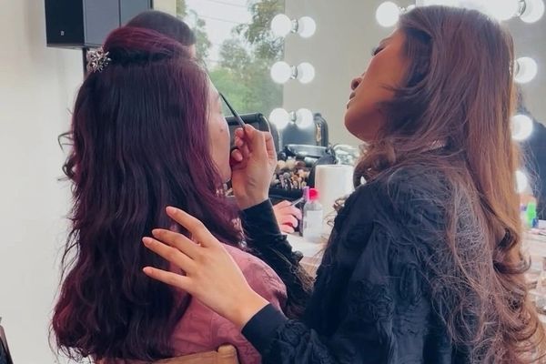 A makeup artist doing a guest's makeup in a director's chair