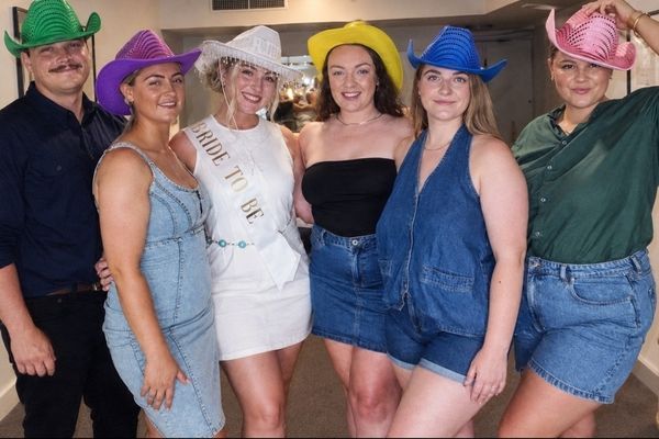 A bride to be in white with her crew in bright cowgirl hats and denim