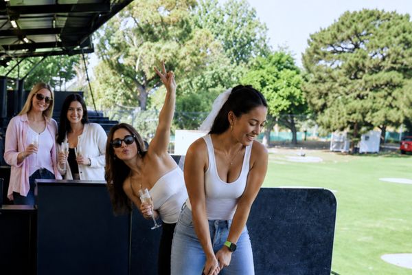 Friends cheering as a friend swings a driver at the driving range bays