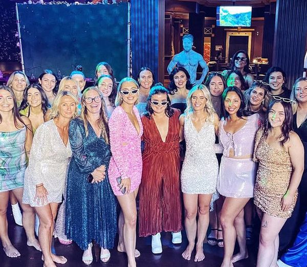 A big hens group dressed up at the male revue show with a performer behind