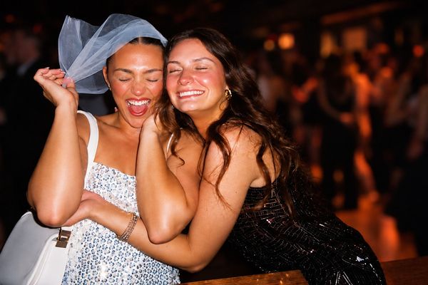 A laughing bride to be in a short veil hugs a friend on a night out