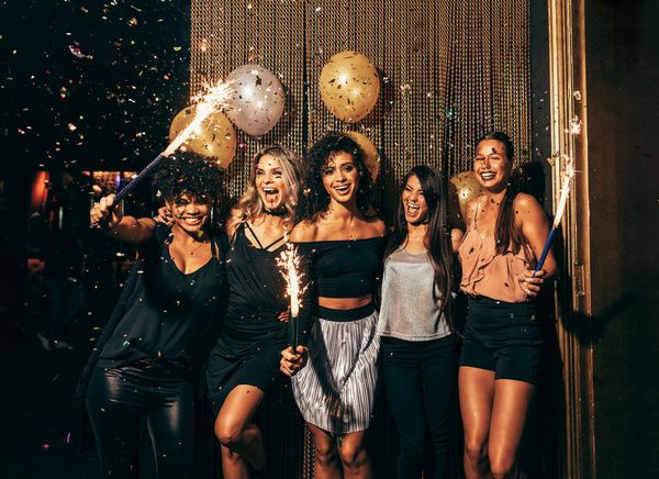 Five gorgeous ladies stand and pose for a group portrait in a private room with balloons and a sparkling backdrop