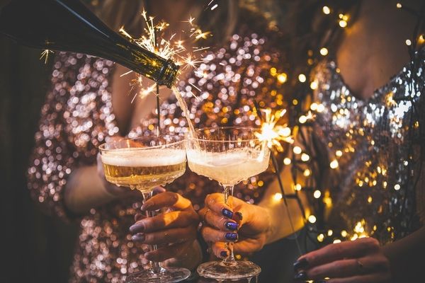 women in sparkly dresses with sparkles holding glasses as they are poured bubbly