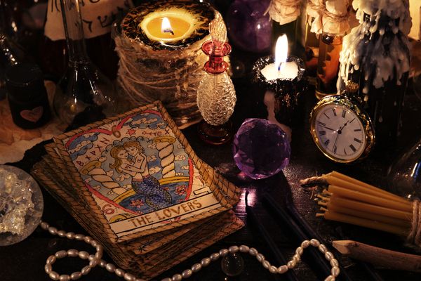 A tarot deck by candlelight with a clock, crystals and pearls