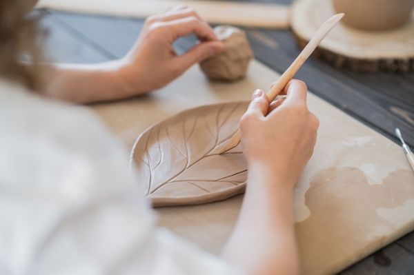 A gorgeous hen polishes her leaf-shaped plate with a brush at the clay pottery workshop