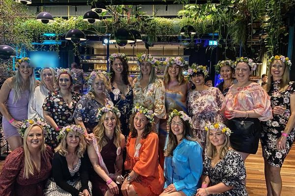 A big hens group all wearing flower crowns in a leafy green venue