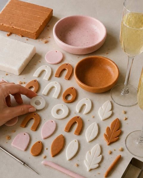 Clay shapes and small pink and terracotta clay dishes on a table beside a glass of bubbles