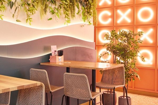 Pink neon letter wall, hanging greenery and high tables in a bar room