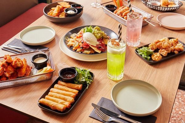 A table of share plates, spring rolls, wings and cocktails by the window
