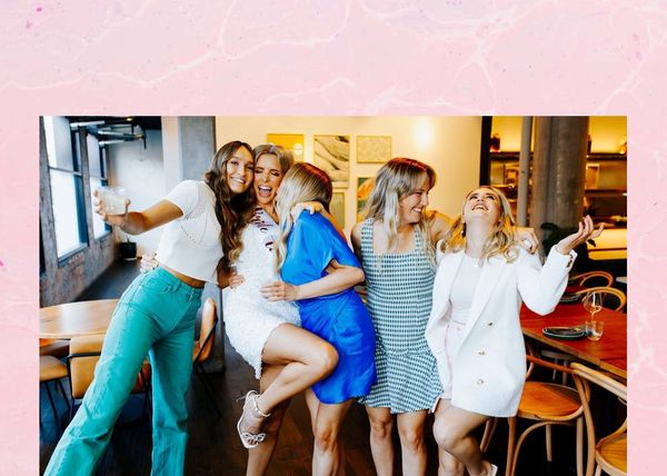 The bride in her sash hugging her friends at a restaurant table